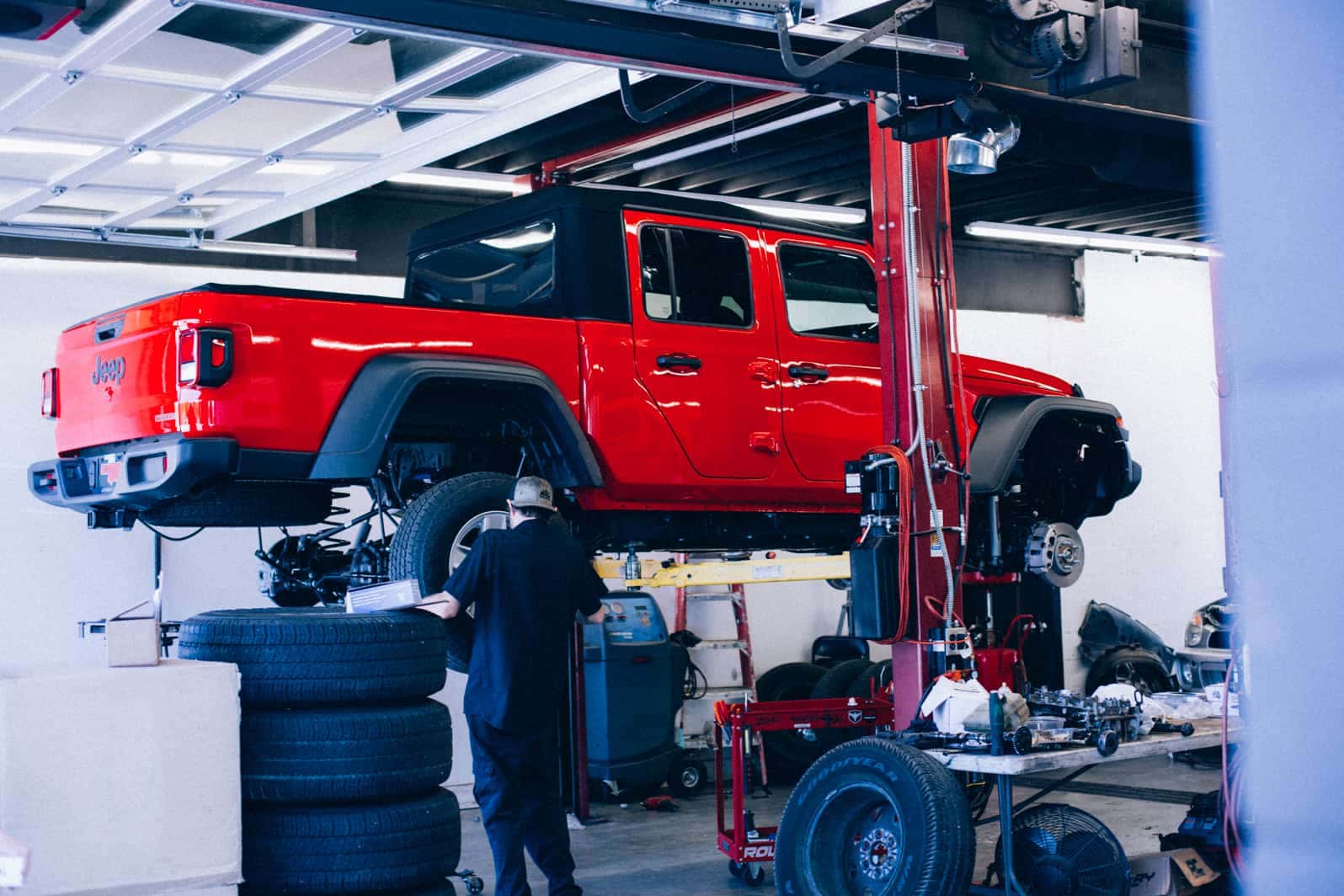 Technician installing a lift kit on a red Jeep Gladiator in the Ultimate Rides shop